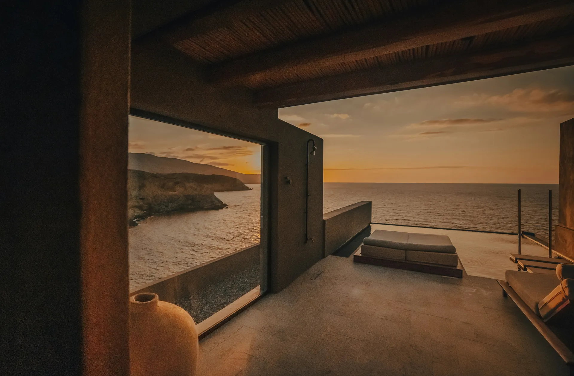 A boutique hotel room opening onto the sea at sunset